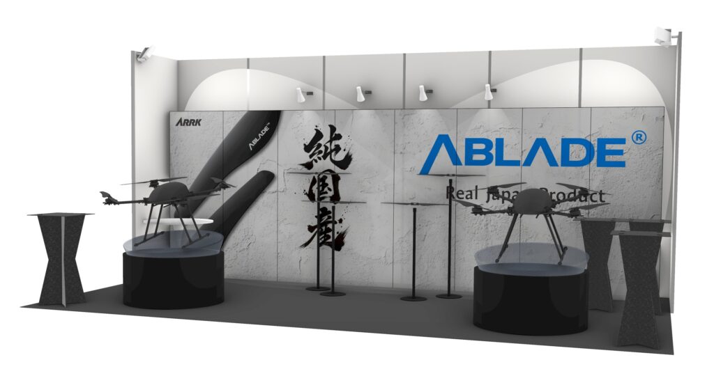 Exhibition booth showing two quadcopter drones on round platforms with ABLADE branding on a patterned backdrop.