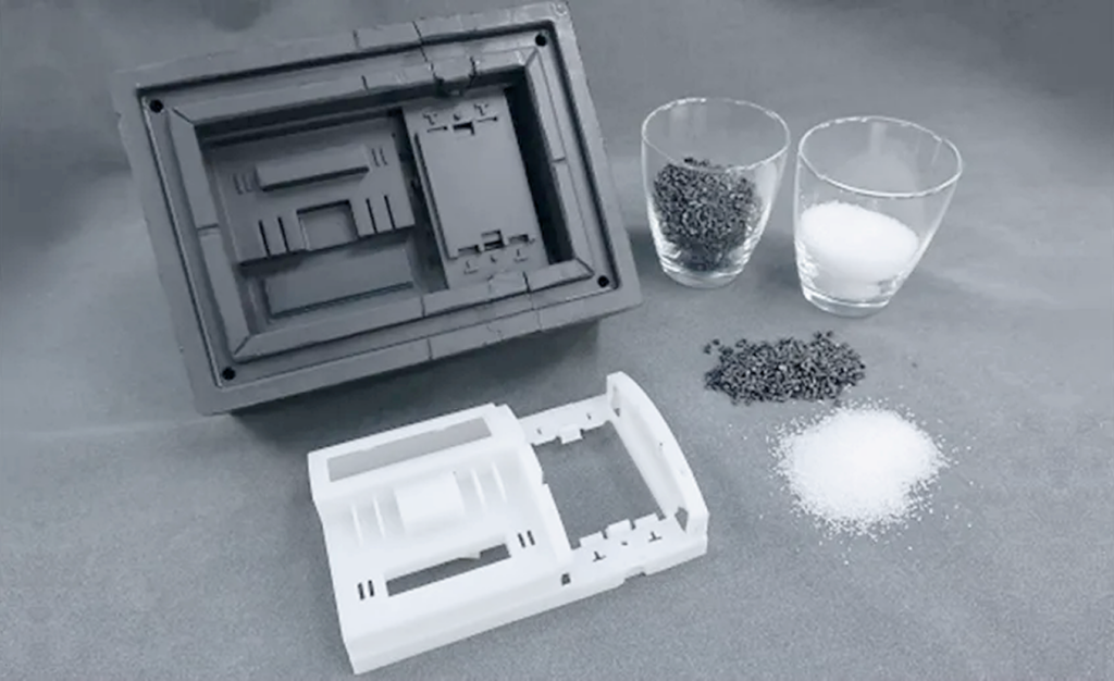 Disassembled gray safe-like device with a white inner shell on a gray surface, beside two glass cups containing pepper and salt and small piles of each nearby.