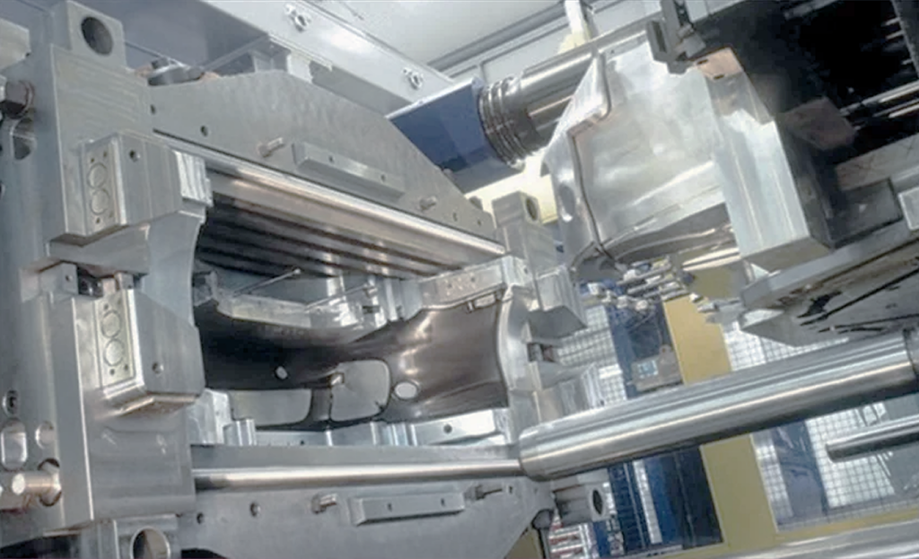 Close-up of large, metallic manufacturing machinery with polished rails and cylindrical components in an industrial setting